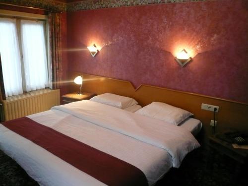a bedroom with a large bed and two lights on the wall at Hotel La Barakka in Lokeren
