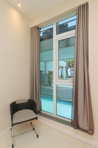 a chair in a room with a window and a pool at ALIZE CUMBUCO in Cumbuco