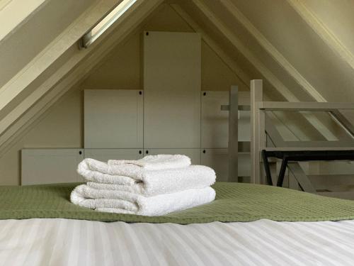 een stapel handdoeken bovenop een bed bij Vakantiehuis Bed en Breakfast in de Tuin in Beilen