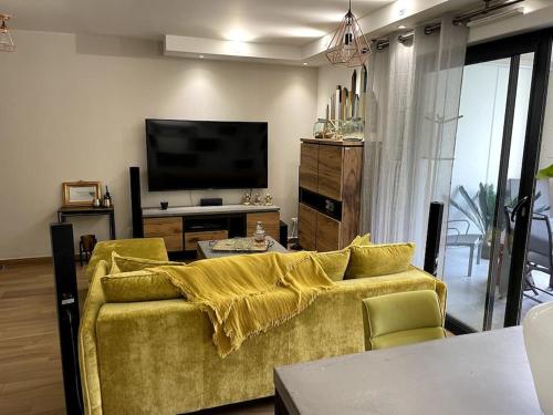 ein Wohnzimmer mit einem gelben Sofa und einem TV in der Unterkunft Appartement calme proche Bastia in Cardo
