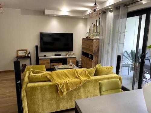 salon z żółtą kanapą i telewizorem w obiekcie Appartement calme proche Bastia w mieście Cardo