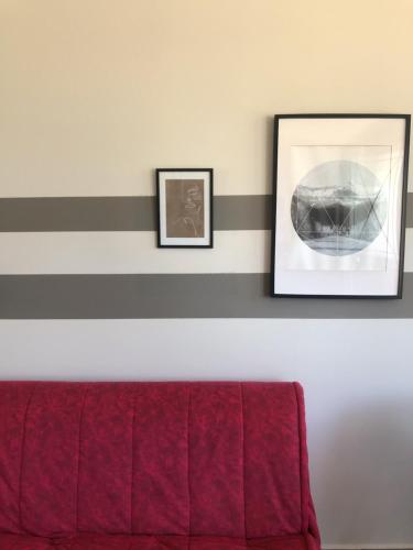 a red couch in a room with two pictures on the wall at siviri suites in Siviri