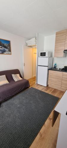 een kleine kamer met een bed en een keuken bij le Soleil des Neiges in La Foux