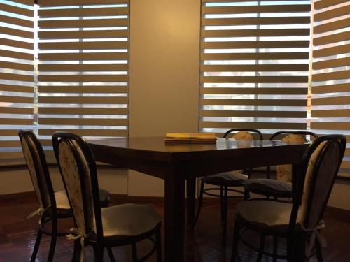 a dining room table with chairs and windows at Tu experiencia comienza aquí Departamento 3D 3C Achumani a pasos de la calle 29 in La Paz