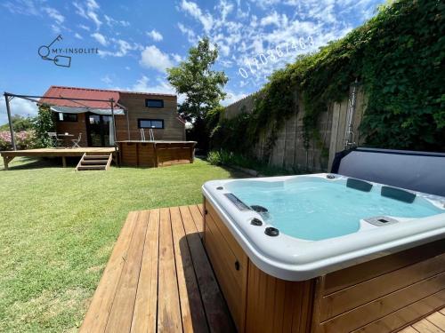 エーグ・モルトにあるmyinsolite - Tiny-house, jacuzzi, brasero, piscineの庭園のデッキに座ってホットタブを利用できます。