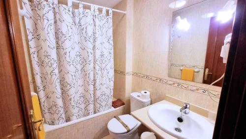 a bathroom with a sink and a toilet and a shower curtain at La Graciosa Camelia Beach Vistas Mar in Caleta de Sebo