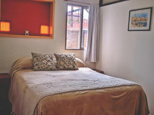 1 dormitorio con 1 cama con 2 almohadas y ventana en HERMOSO ALOJAMIENTO TEMPORARIO KAYA en Villa Giardino