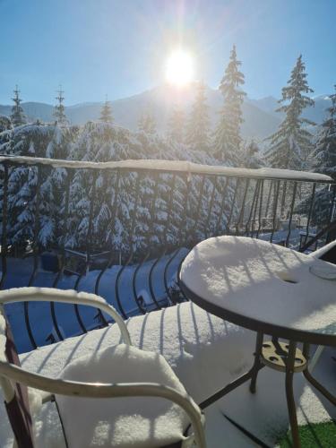 a table and chairs on a balcony with snow covered trees at Pokoje gościnne Zosia in Kościelisko