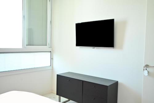 a bedroom with a tv on a white wall at Modern 2BR Condo with Sea Views at Isrotel by HolyGuest in Tel Aviv
