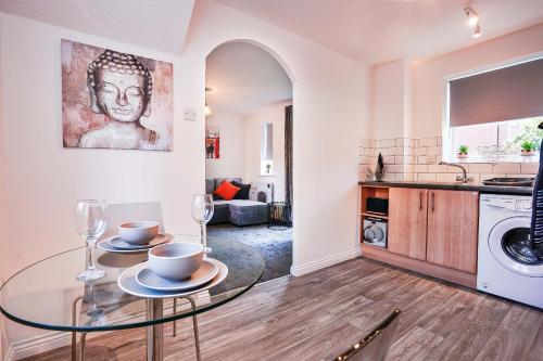 a living room with a glass table and a kitchen at Victoria Gardens in Colchester