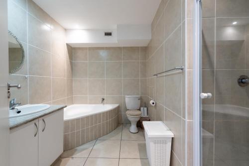a bathroom with a tub and a toilet and a sink at INDIGO BAY 24 in Margate
