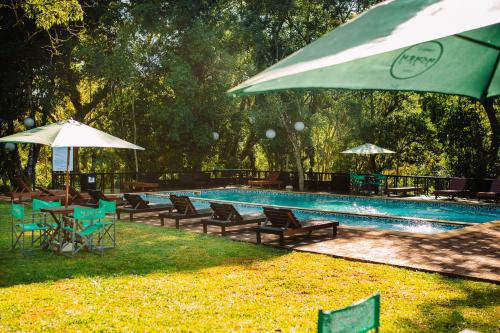 a swimming pool with chairs and umbrellas and a pool at Cabañas complejo Ysyry Misiones in Puerto Victoria
