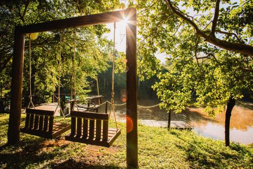two benches on a swing by a river at Cabañas complejo Ysyry Misiones in Puerto Victoria
