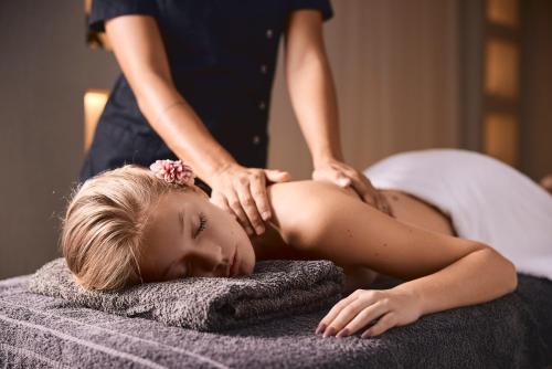 Una mujer recibiendo un masaje de una chica en una cama en Garifalakis Comfort Rooms, en Pollonia
