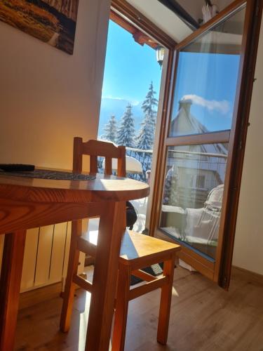 a wooden table and chair in a room with a window at Pokoje gościnne Zosia in Kościelisko