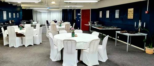 une salle à manger avec des tables et des chaises blanches dans l'établissement Hotell Tre Systrar, à Eskilstuna