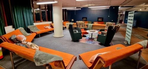 une chambre avec des rangées de chaises et de tables orange dans l'établissement Hotell Tre Systrar, à Eskilstuna