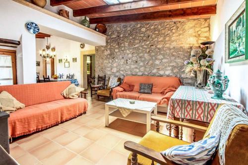 a living room with orange couches and a stone wall at Villa Rosita in Pollença