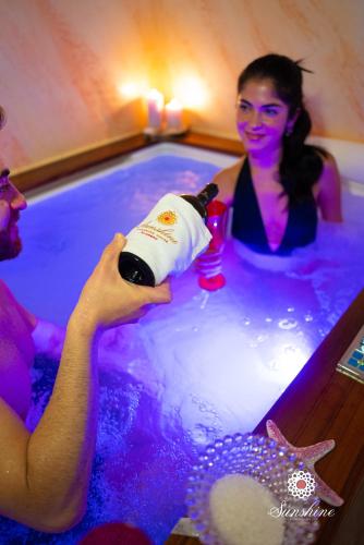 a woman holding a bottle of wine in a bath tub at Sunshine Charming Houses in Alghero