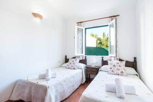 two beds in a room with a window at Villa Dion Bosch in Cala en Bosc