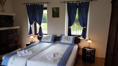 Schlafzimmer mit einem großen Bett und blauen Vorhängen in der Unterkunft Zselic Szíve Parasztház in Simonfa