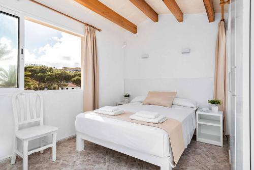 a white bedroom with a bed and a chair at Villa Elizabet in Cala en Forcat
