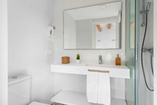 a white bathroom with a sink and a mirror at Villa Elizabet in Cala en Forcat