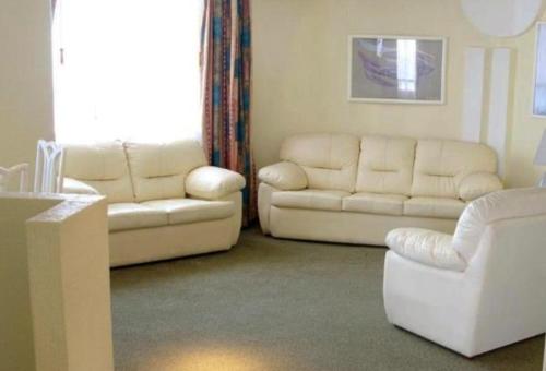 a living room with white furniture and a couch at Hotel Real del Sur in Mexico City