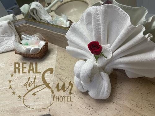 a white towel with a rose on a bathroom counter at Hotel Real del Sur in Mexico City
