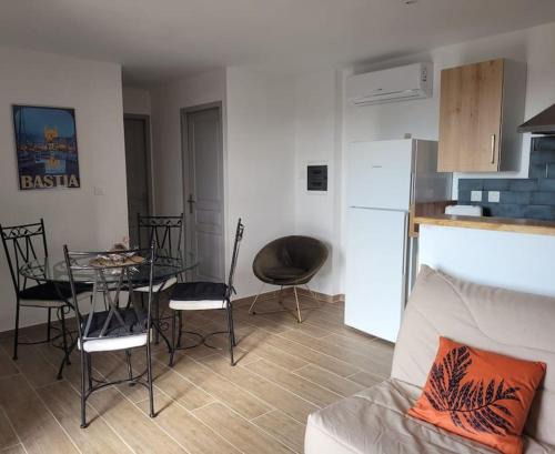 a living room with a table and chairs and a kitchen at Charmant petit logement à 2 km (2 min) de la plage in Belgodère