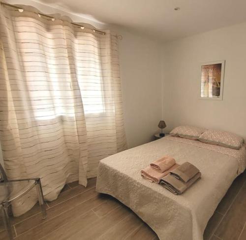 1 dormitorio con 1 cama y una ventana con cortinas en Charmant petit logement à 2 km (2 min) de la plage, en Belgodère