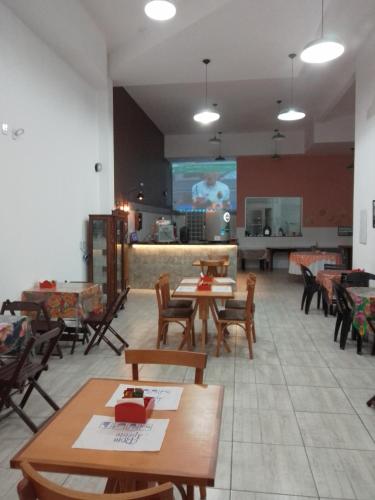 a restaurant with tables and chairs and a screen at Hotel Pousada Santa Maria in Aparecida