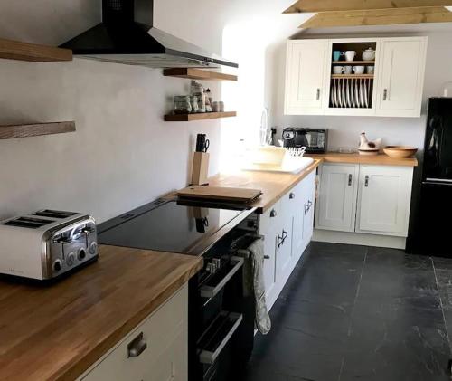a kitchen with white cabinets and a stove top oven at Hallgarden Farmhouse in Otterham