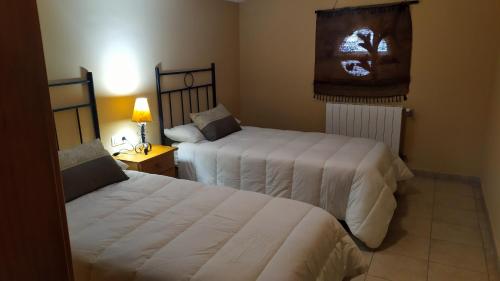 a bedroom with two beds and a table with a lamp at Casas Rurales Fuenmayor in Torres