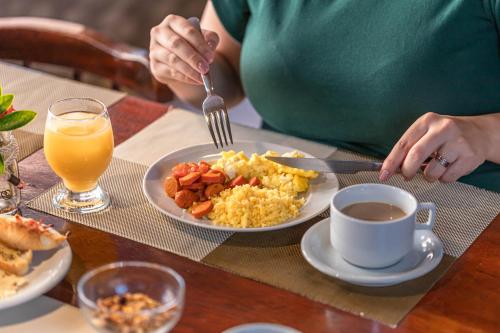 a woman sitting at a table with a plate of breakfast food at Bessa Beach Hotel in João Pessoa