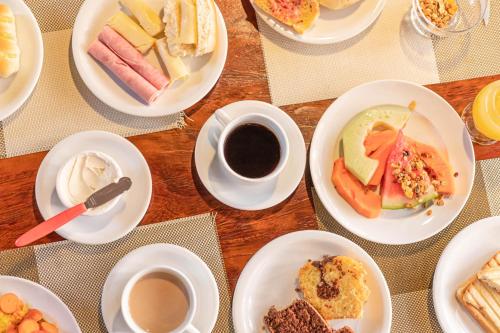 a table with plates of food and cups of coffee at Bessa Beach Hotel in João Pessoa
