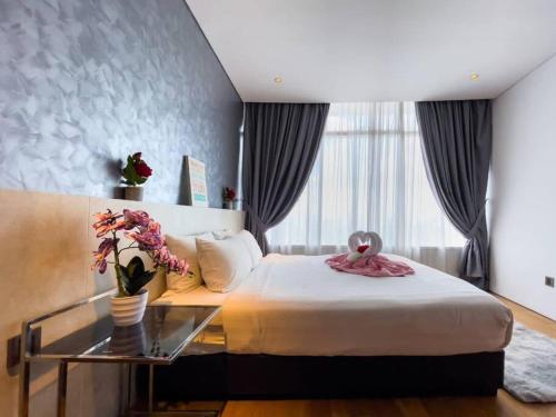 a bedroom with a bed and a glass table with flowers at The Luxury Penthouses Kuala Lumpur in Kuala Lumpur