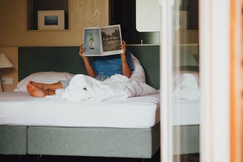 a person laying on a bed reading a book at Pension Obertrum am See in Obertrum am See