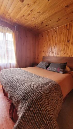 - une chambre avec un lit dans une pièce en bois dans l'établissement Cabaña Kurrüf - Los Arrayanes de San Juan, à Quellón