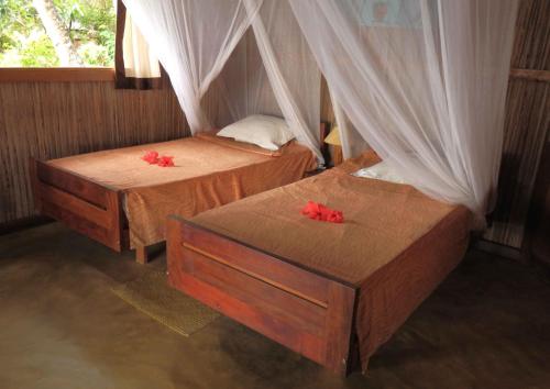 two beds in a room with red flowers on them at Maningory in Ile aux Nattes