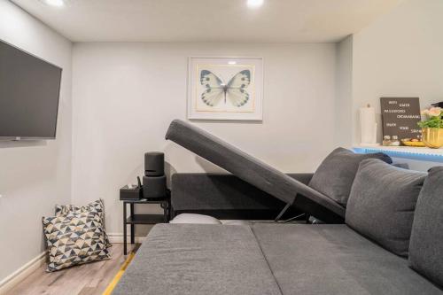 a living room with a couch and a butterfly picture on the wall at Cozy nest basement unit in Hamilton