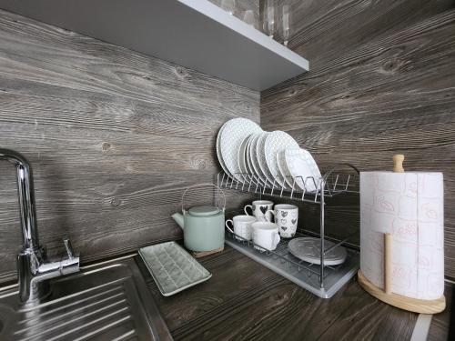 布德瓦Budvariana Apartments的厨房配有水槽和带碗碟的架子