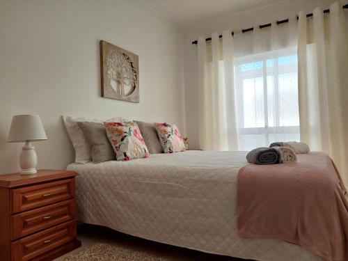a bedroom with a bed with a dresser and a window at Casa da Alegria - apartamento acolhedor no centro de Olhão in Olhão