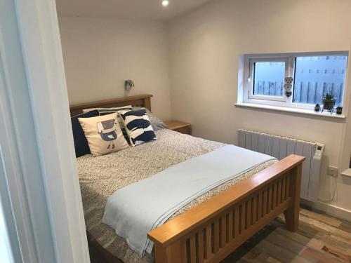 1 dormitorio con cama con almohadas y ventana en Hideaway Cabin for two on edge of New Forest en Hinton