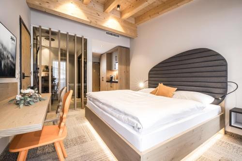 ein Schlafzimmer mit einem großen Bett und einem Schreibtisch in der Unterkunft Alpine Collection Wildschönau am Paraglidinglandeplatz Markbachjoch, Nähe Skiwelt Wilder Kaiser - Brixental in Niederau