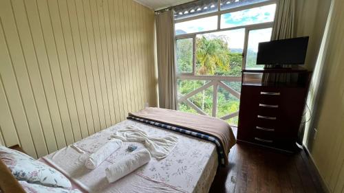 a small bedroom with a bed and a window at 746 Pousada in Nova Friburgo