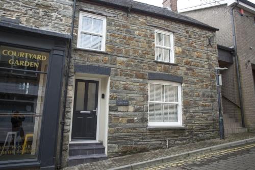 a brick building with a black door and windows at Castle Cottage in Cardigan