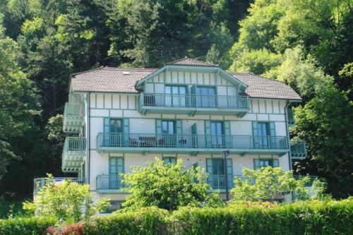 Casa blanca grande con balcones y árboles en Le pavillon du lac en Duingt