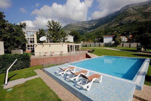 a swimming pool with two lounge chairs and a house at Villa Sutomore in Sutomore