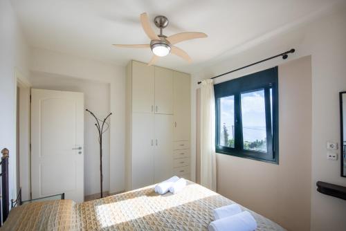 a bedroom with a bed with a ceiling fan at Portela Apartments Kampoula in Keratokampos